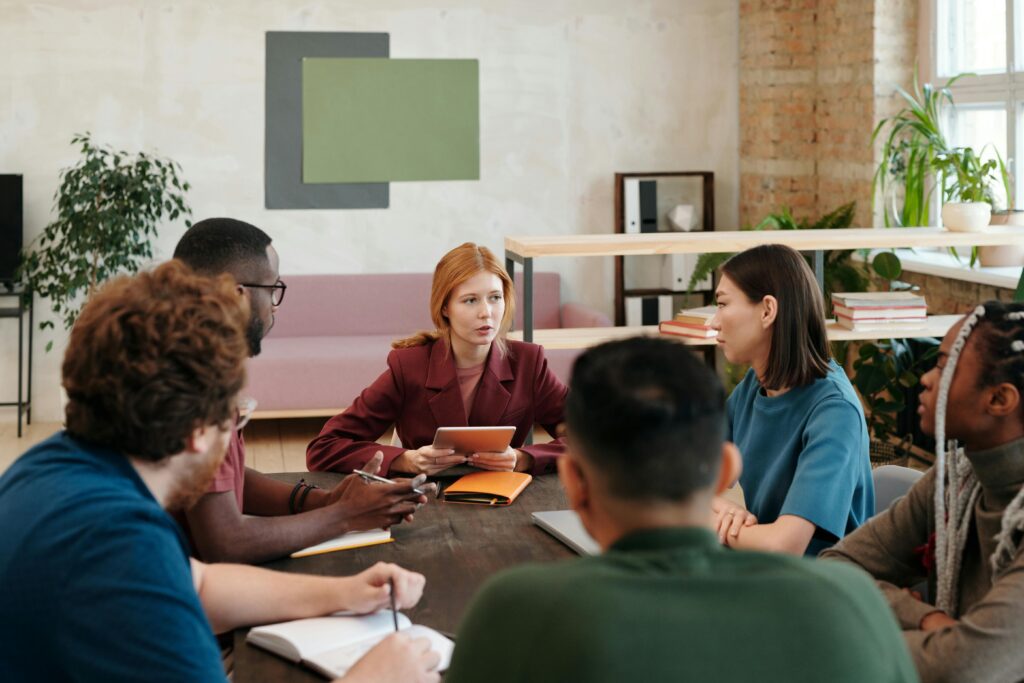 Beispielbild für unsere Leistungen für die Gesellschaft: Menschen, die zusammen an einem Tisch sitzen und diskutieren